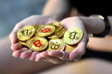 Hands holding a pile of physical Bitcoin tokens, representing the moment a first purchase becomes real